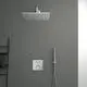 Duschbereich von Ideal Standard mit einer großen, rechteckigen Regenbrause an einer grauen Wand. An der Seite ein Handbrause mit Halterung und Bedienelemente für die Wassertemperatur.